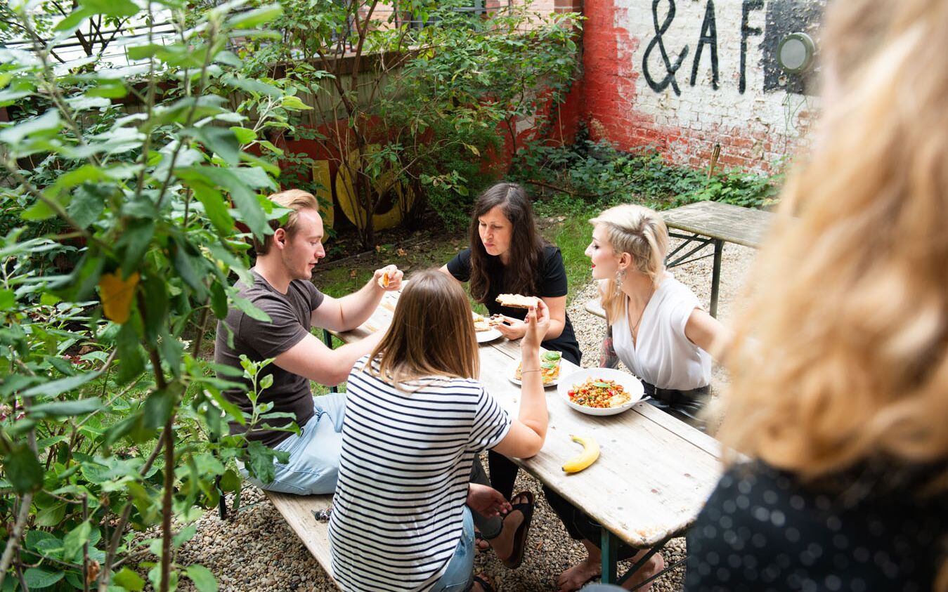Menschen sitzen im Garten und essen.