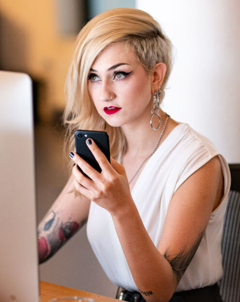Frau sitzt vor einem Computer und erstellt eine Website.
