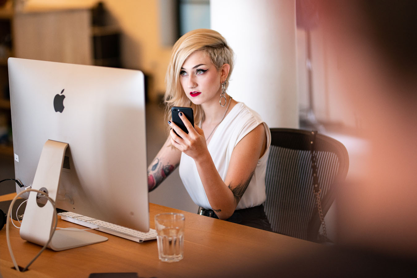 Frau sitzt vor einem Computer und erstellt eine Website.