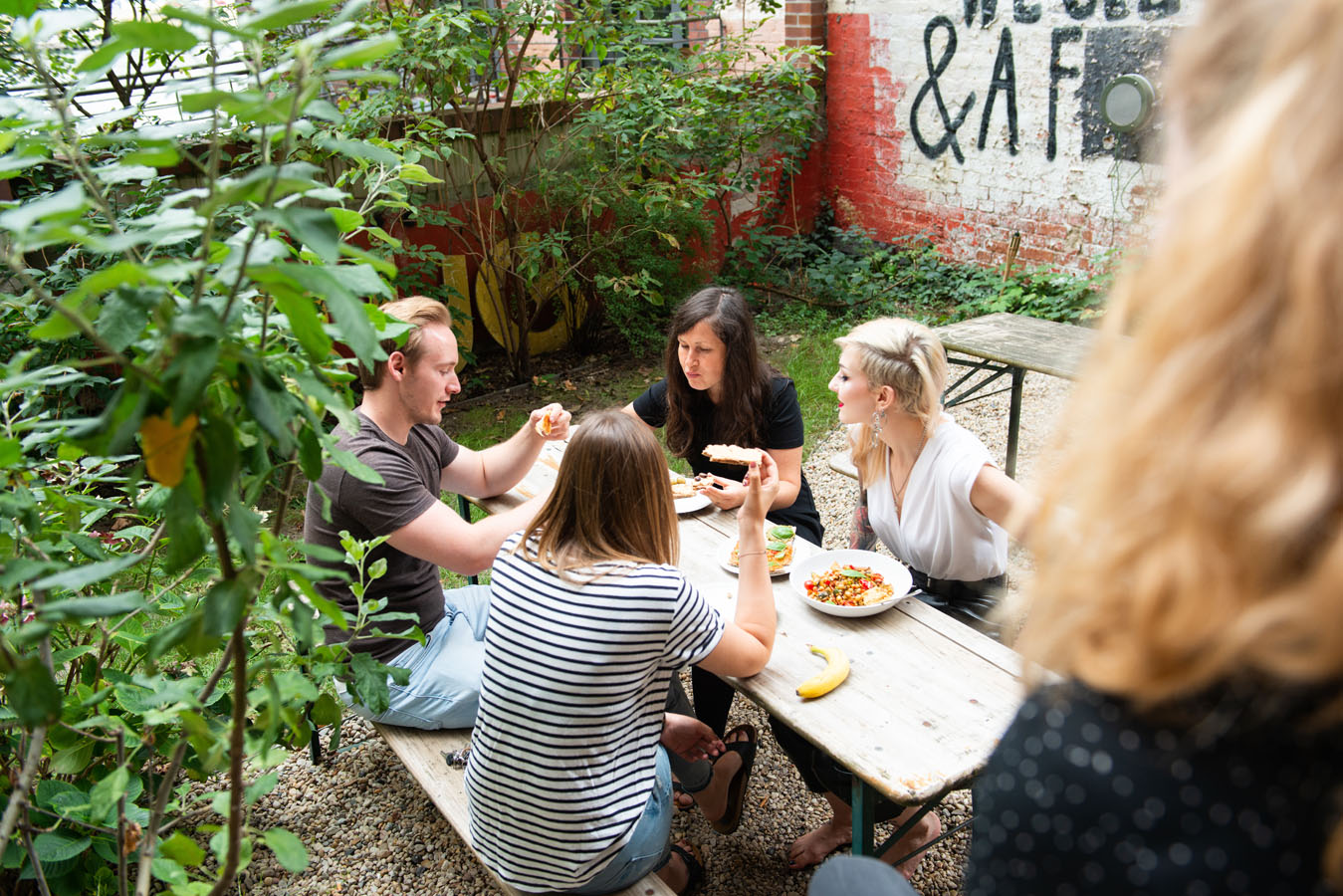 Menschen sitzen im Garten und essen.